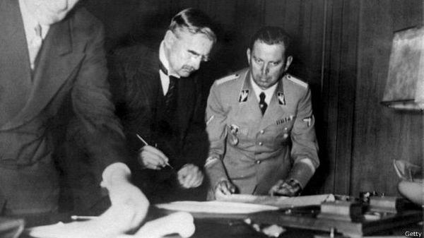 Невилл Чемберлен подписывает Мюнхенское соглашение (справа Мартин Борман)