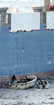 сомалийские пираты в маленьких лодках угоняют грузовое судно