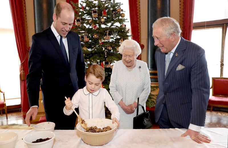 королева Елизавета II, принц Чарльз, принц Уильям и принц Джордж заняты замешиванием теста рождественского пудинга для британских ветеранов
